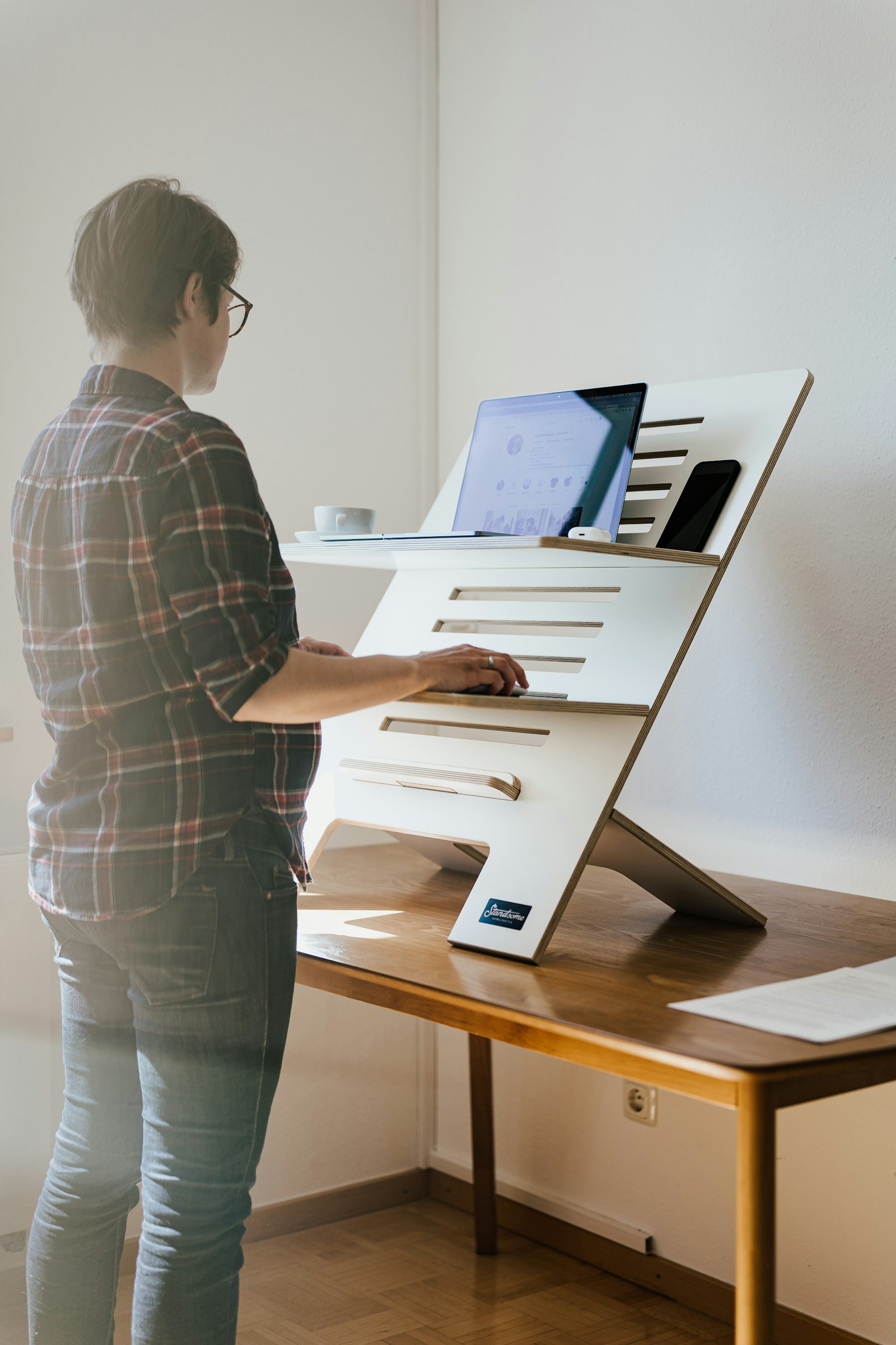Person using a standing desk converter with a laptop on a small home office table