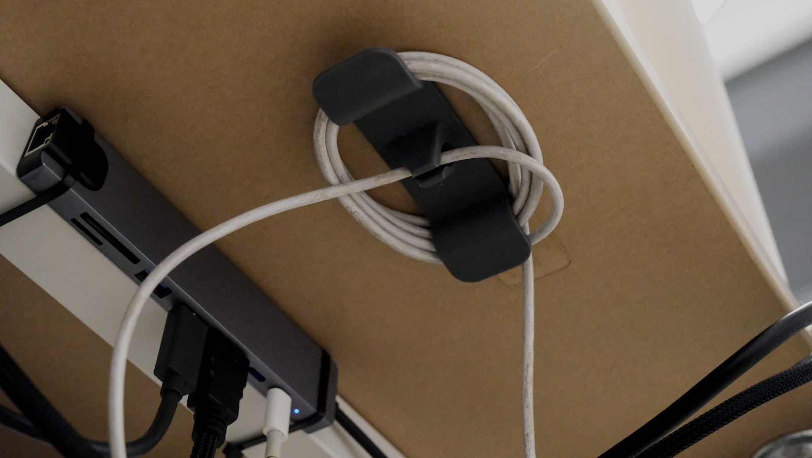Cable clip organizing coiled charging cables neatly under a desk