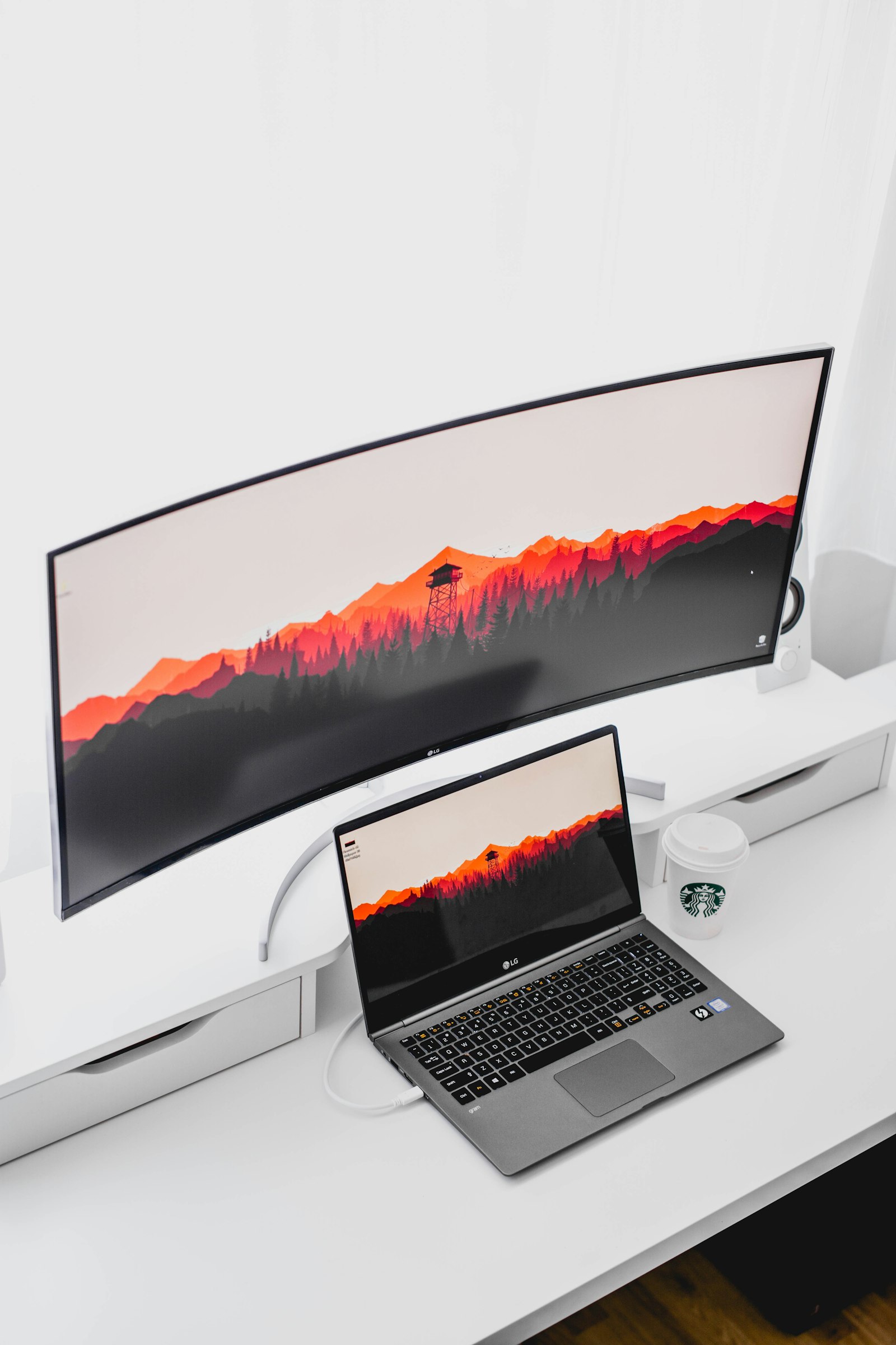 Laptop connected to a curved external monitor on a white desk