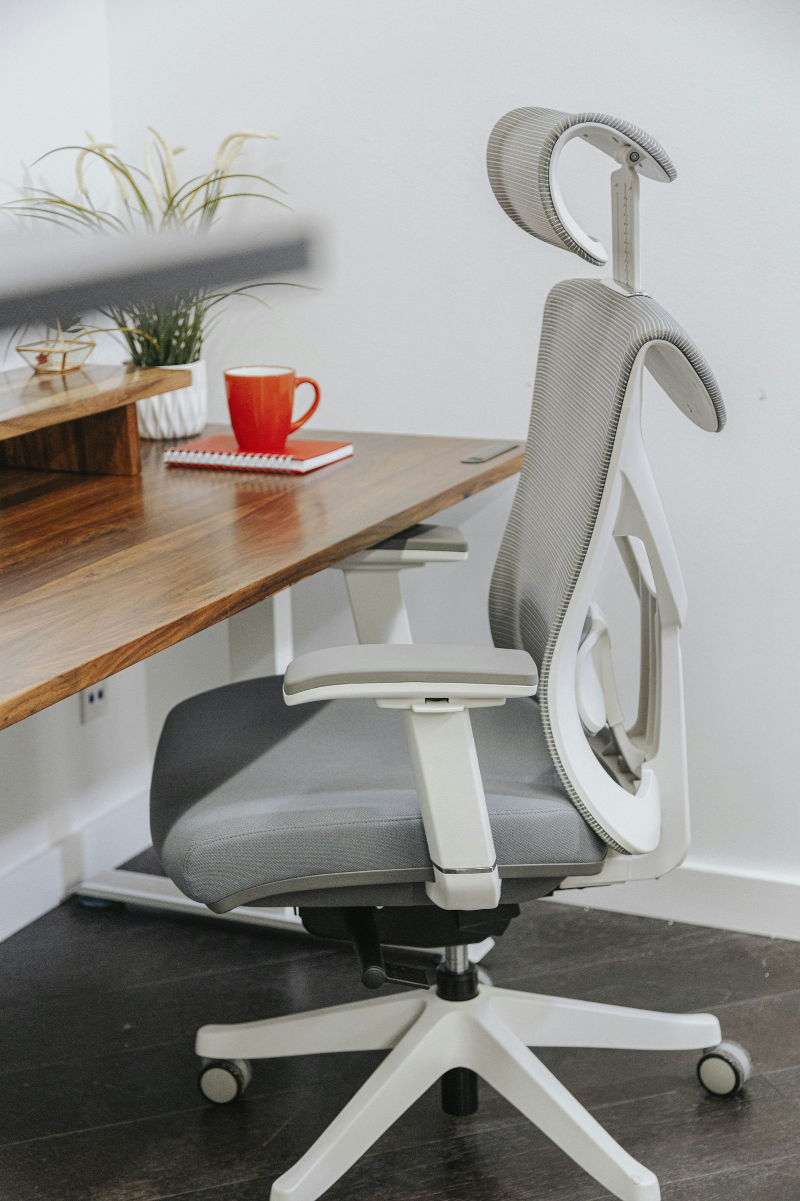 Gray ergonomic office chair positioned at a wooden desk