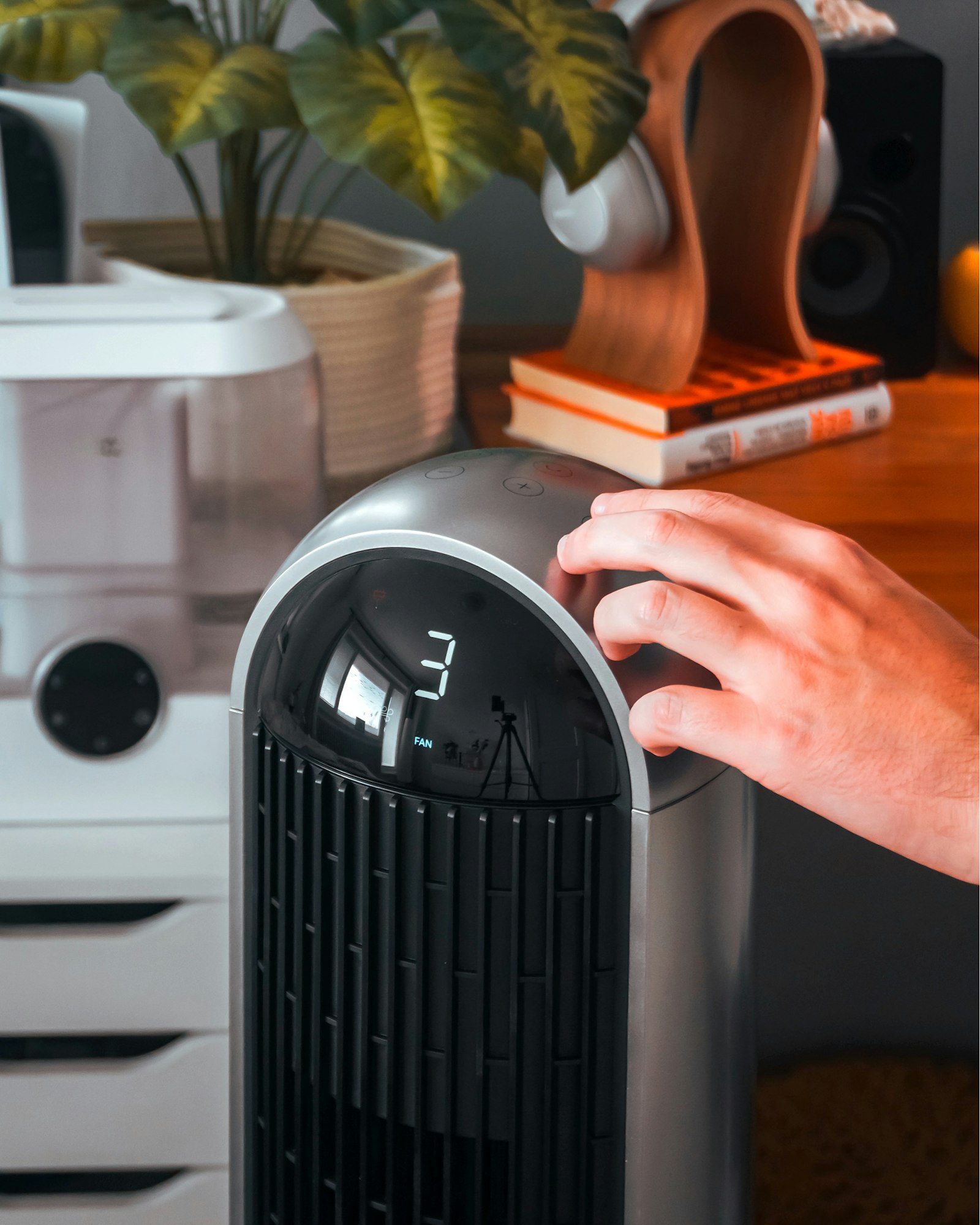 Hand adjusting the controls on a small silver desktop air purifier