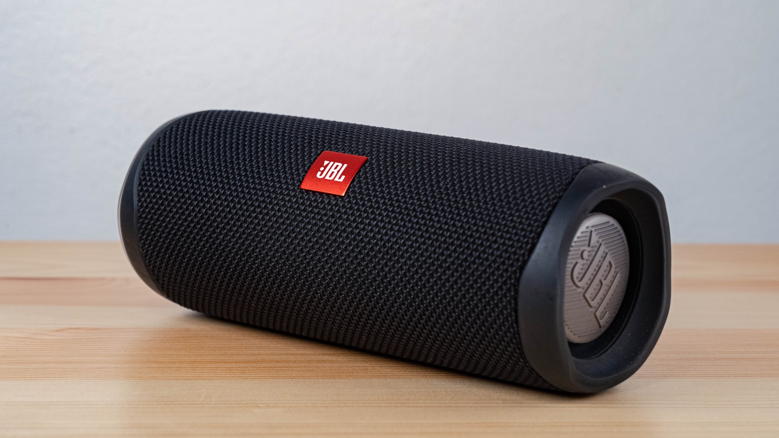 Black JBL portable Bluetooth speaker with red logo on a wooden table