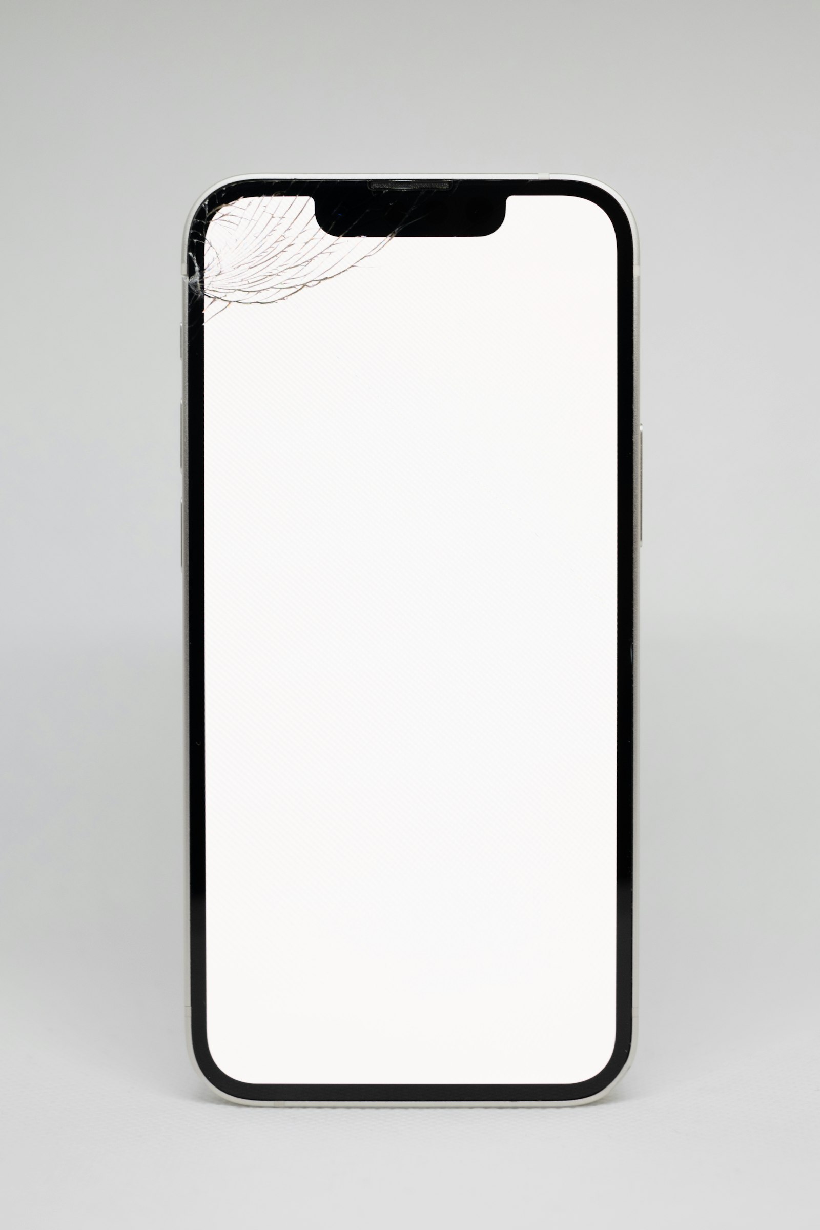 Phone screen with a spider-web crack in the top corner from a drop