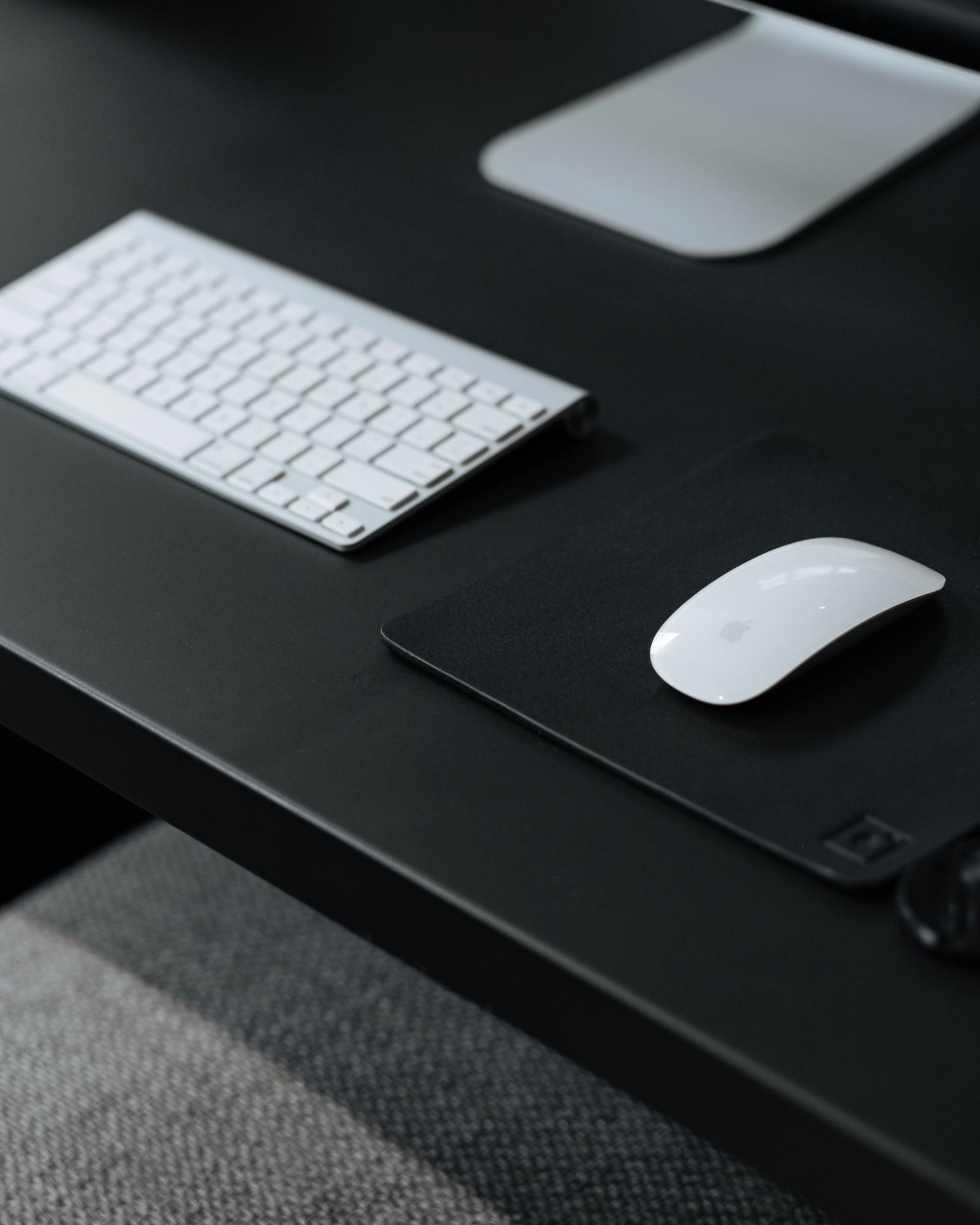 Wireless keyboard and mouse on a desk next to a laptop
