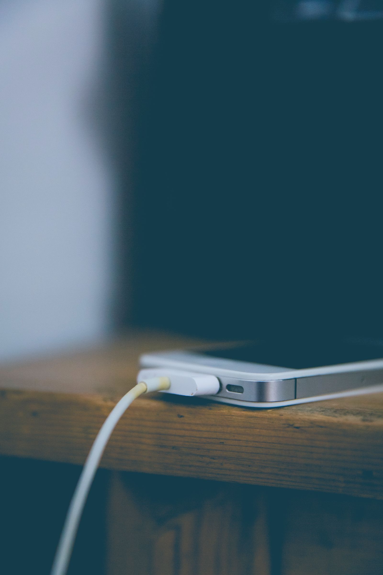 Smartphone charging on a wooden desk