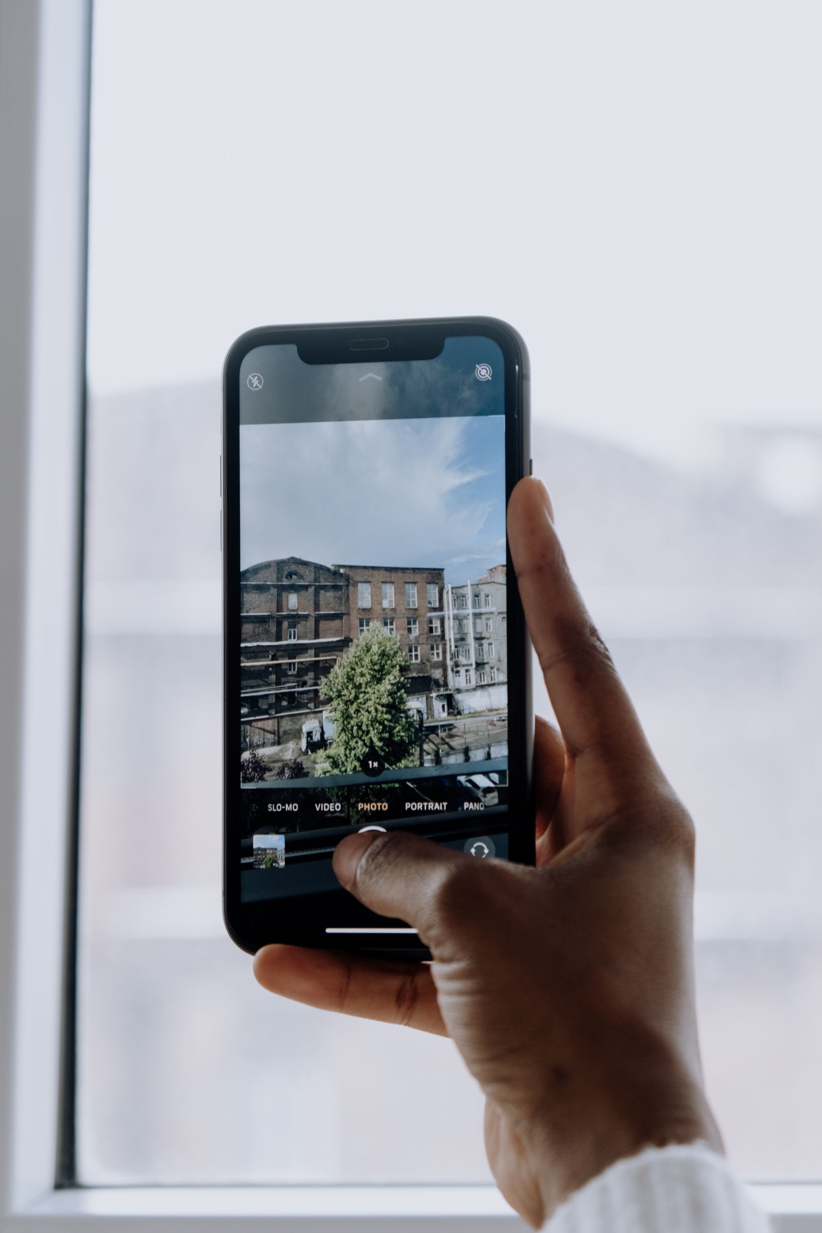 Hand holding a smartphone photographing through a window
