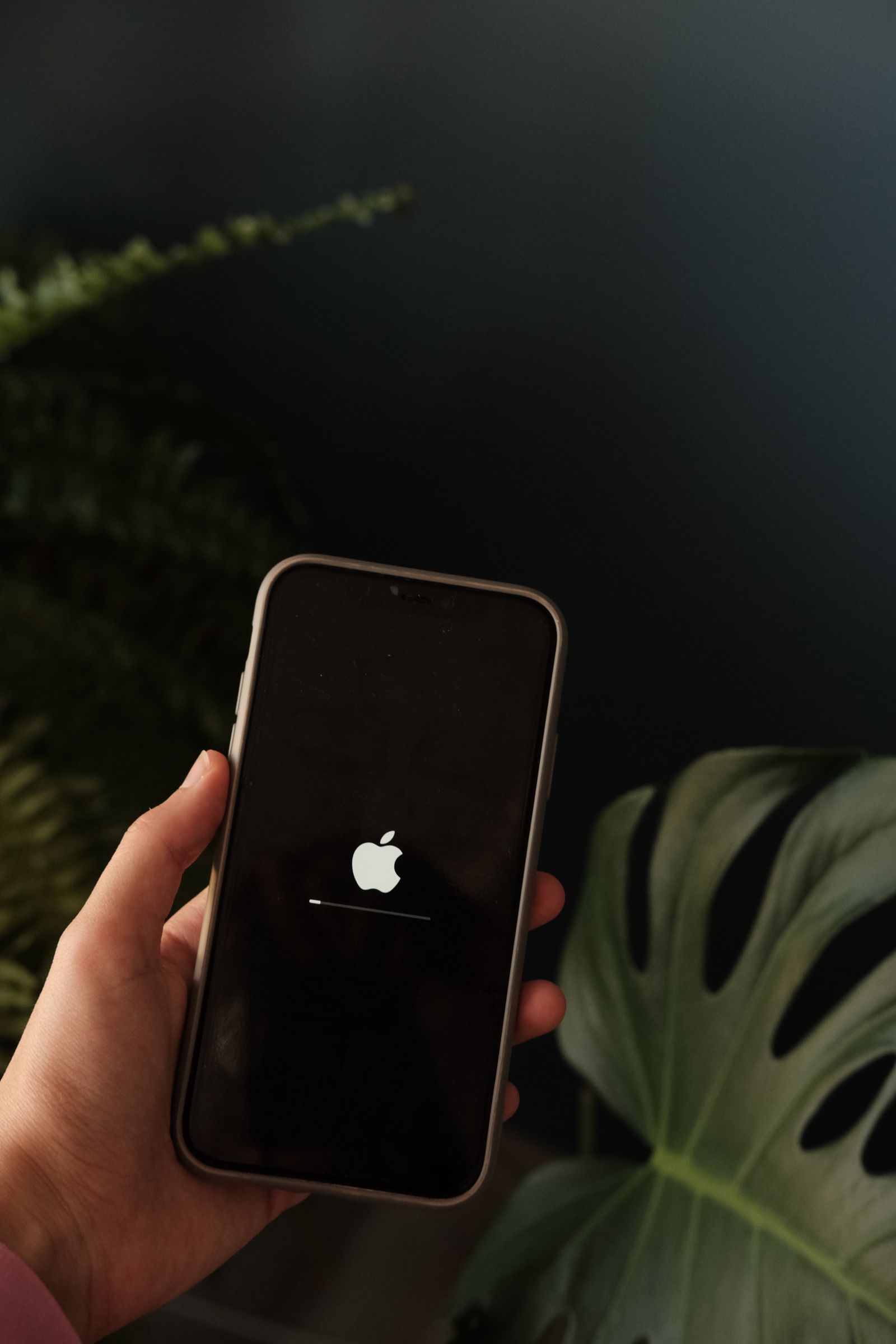 Person holding an iPhone displaying the Apple logo